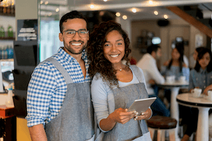 young couple standing in a shop smiling and holding a tablet