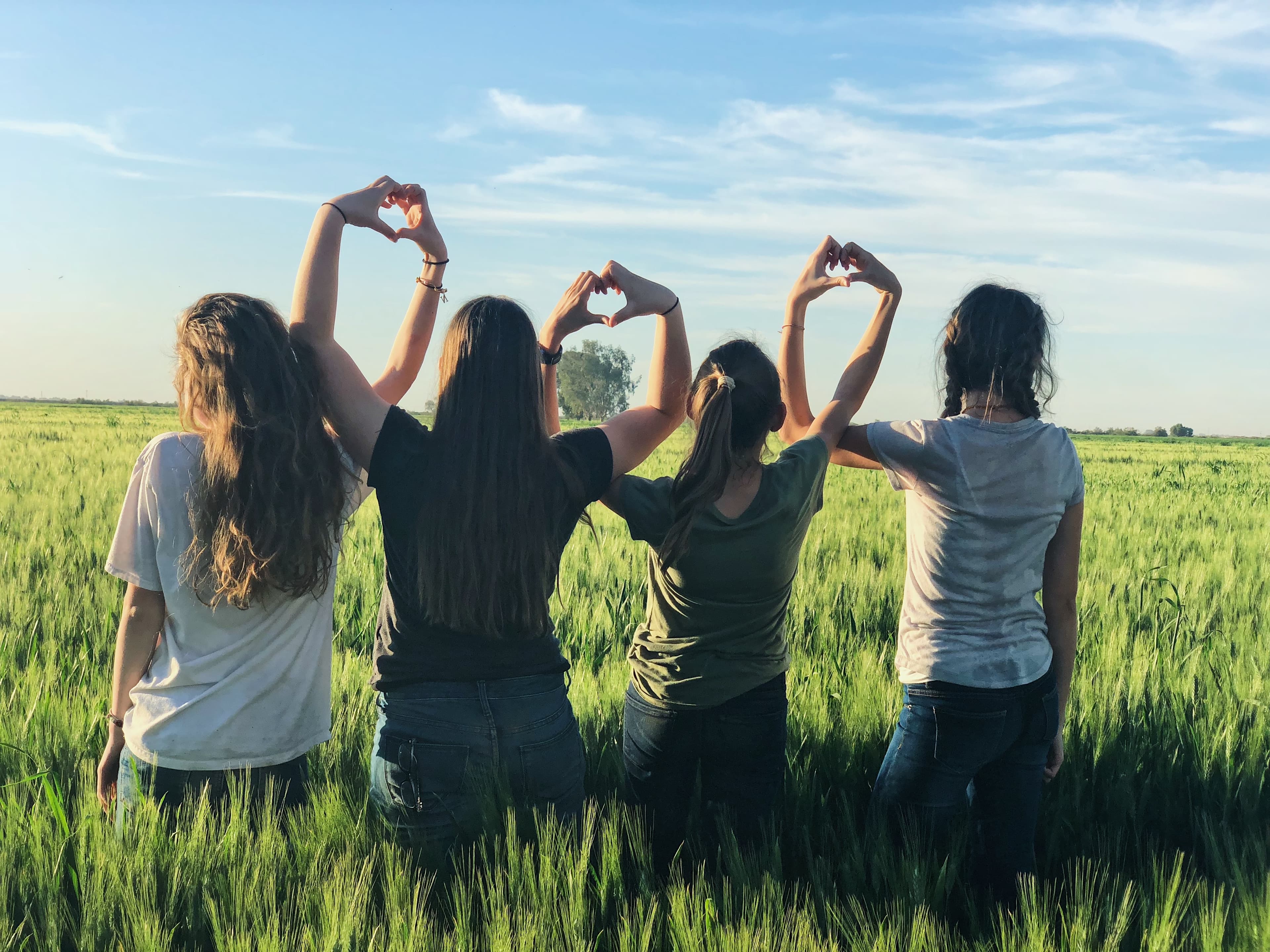 group of people holding each others backs on a bright sunny day.