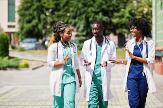 three DPC doctors walking outside talking on a sunny day