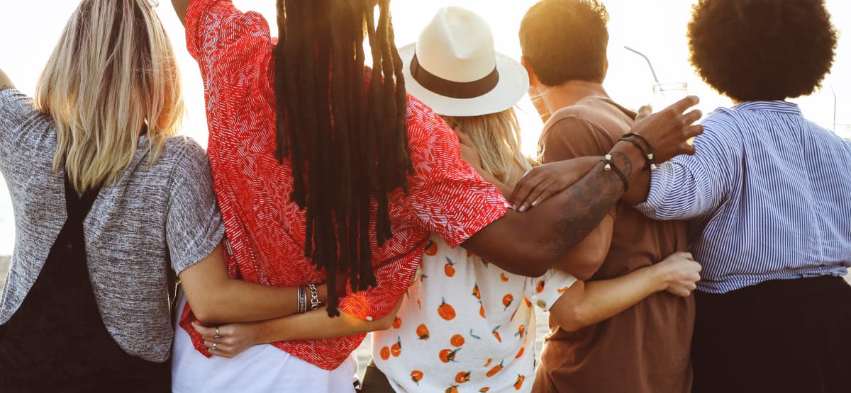 group of people holding each others backs on a bright sunny day.
