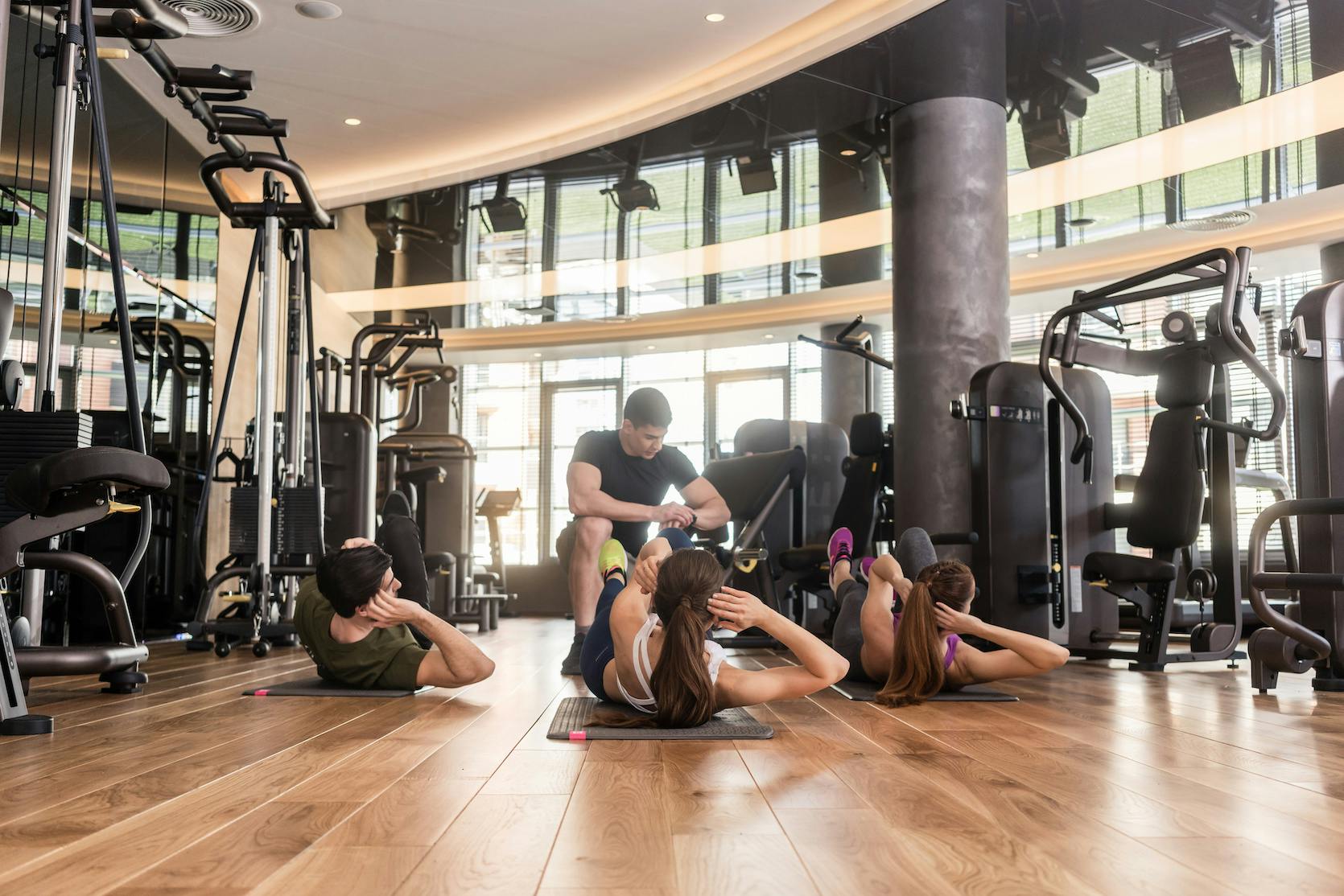 People working out in a well-rounded gym with weights and cardio equipment.