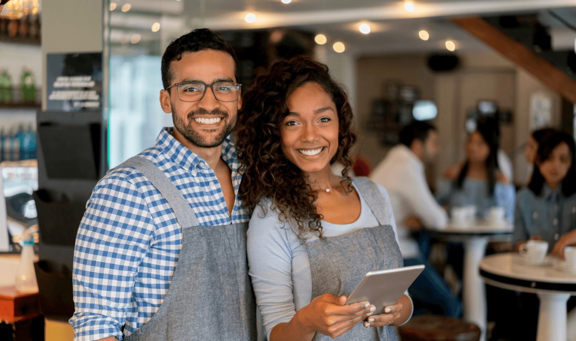 young couple standing in a shop smiling and holding a tablet.