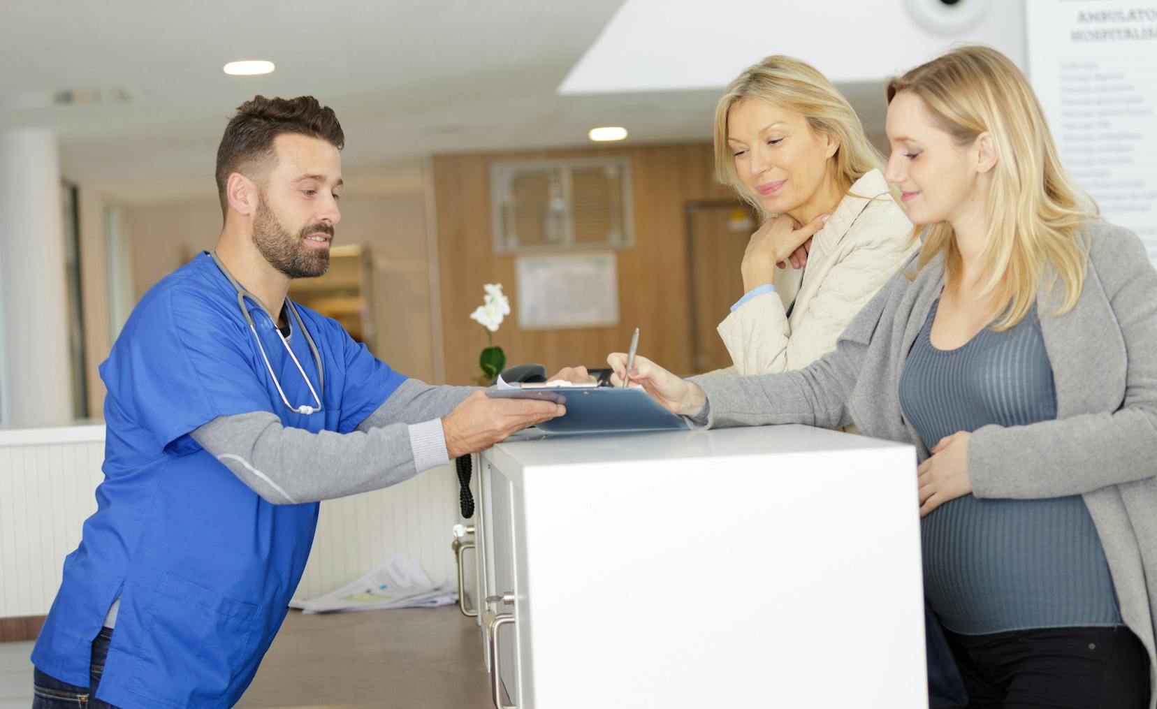A woman at the front desk of a medical office smiling and paying for her care as a cash pay patient.